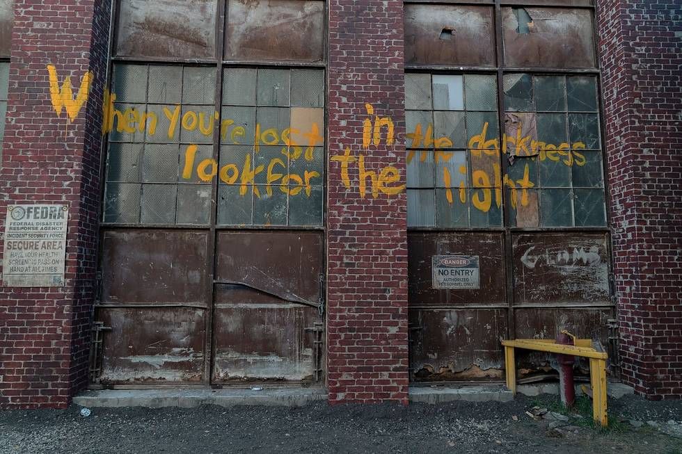 Graffiti on a wall that says “When you’re lost in the darkness look for a light” in a still from The Last of Us season 1
