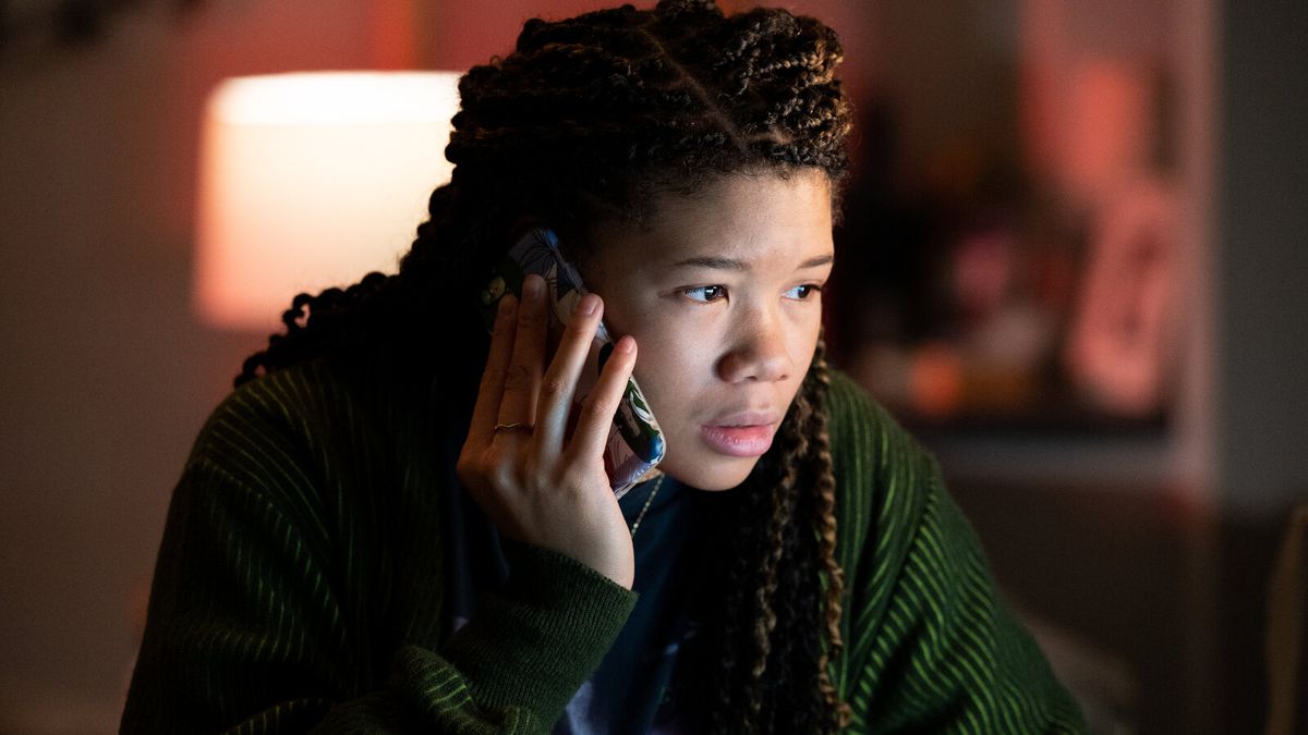 A young woman (Storm Reid) with braided hair holding a cell phone to her ear while staring at a screen off-screen in “Missing.”