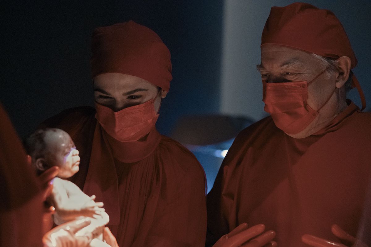 Elliot Mantle (Rachel Weisz) holding a newborn baby with another doctor (Michael McKean) looking over her shoulder