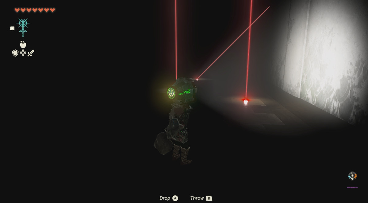 Link shining a flashlight at red lasers. The room is completely dark.
