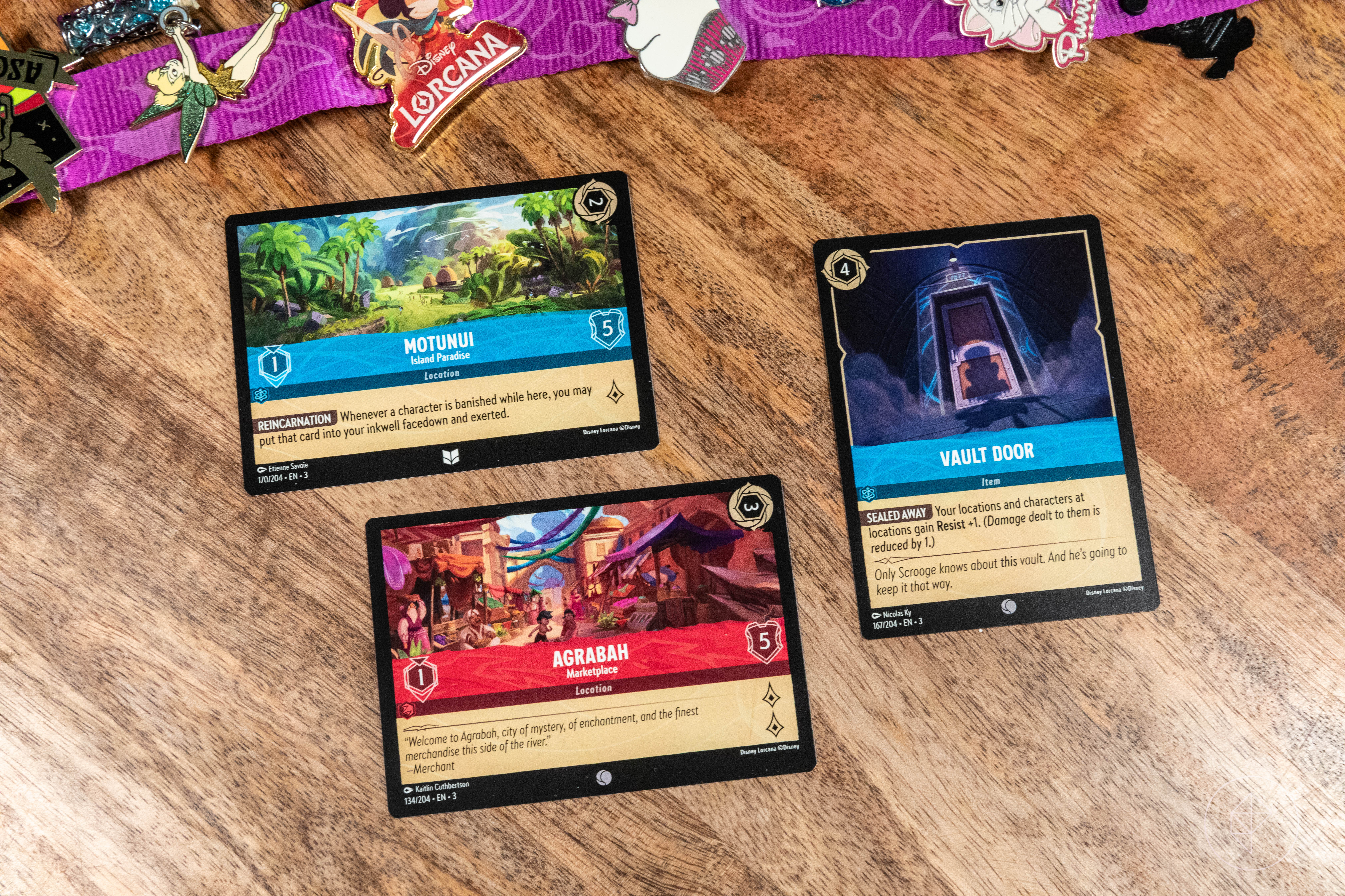 New cards, called location cards, shown here include Motunui and Agrabah. The Vault Door to Scrooge’s money vault is also shown.